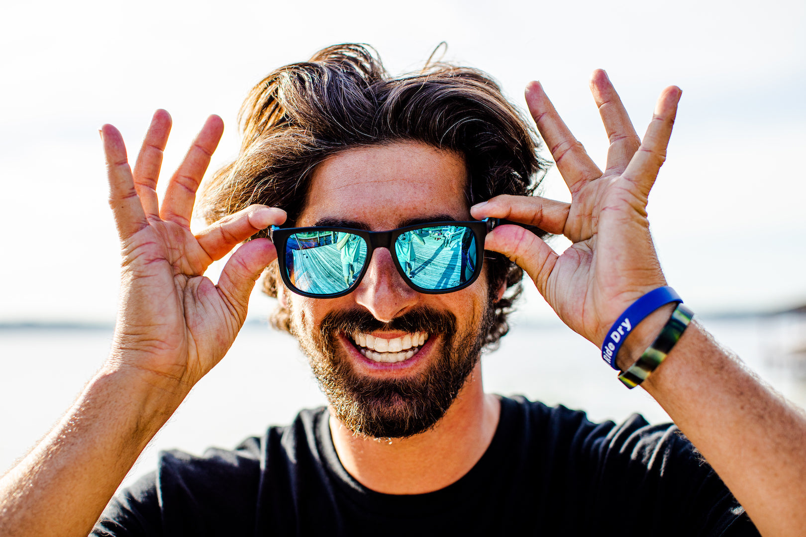 Man wearing mirrored goggles and gray beanie, holding skis in a snowy setting.
