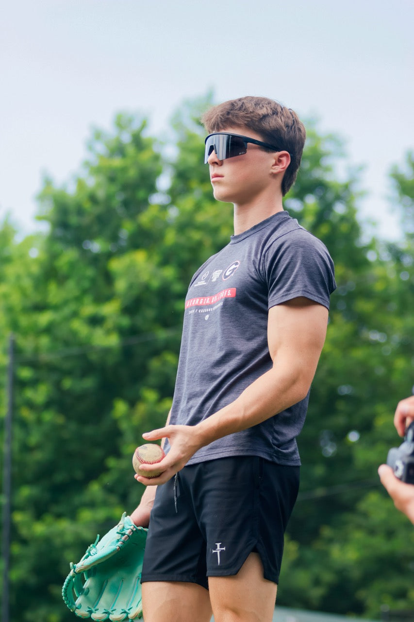 Man wearing mirrored goggles and gray beanie, holding skis in a snowy setting.