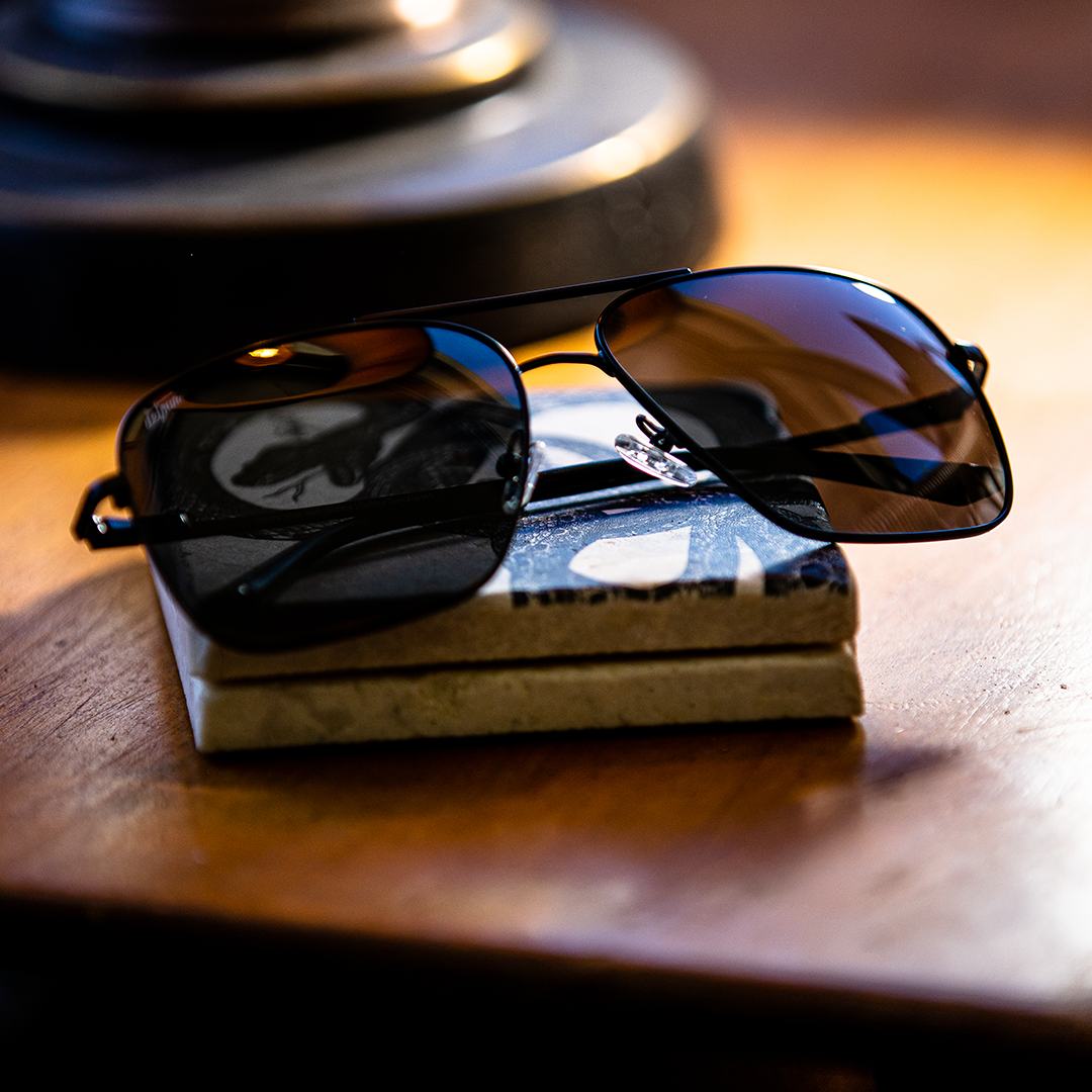 Man wearing mirrored goggles and gray beanie, holding skis in a snowy setting.