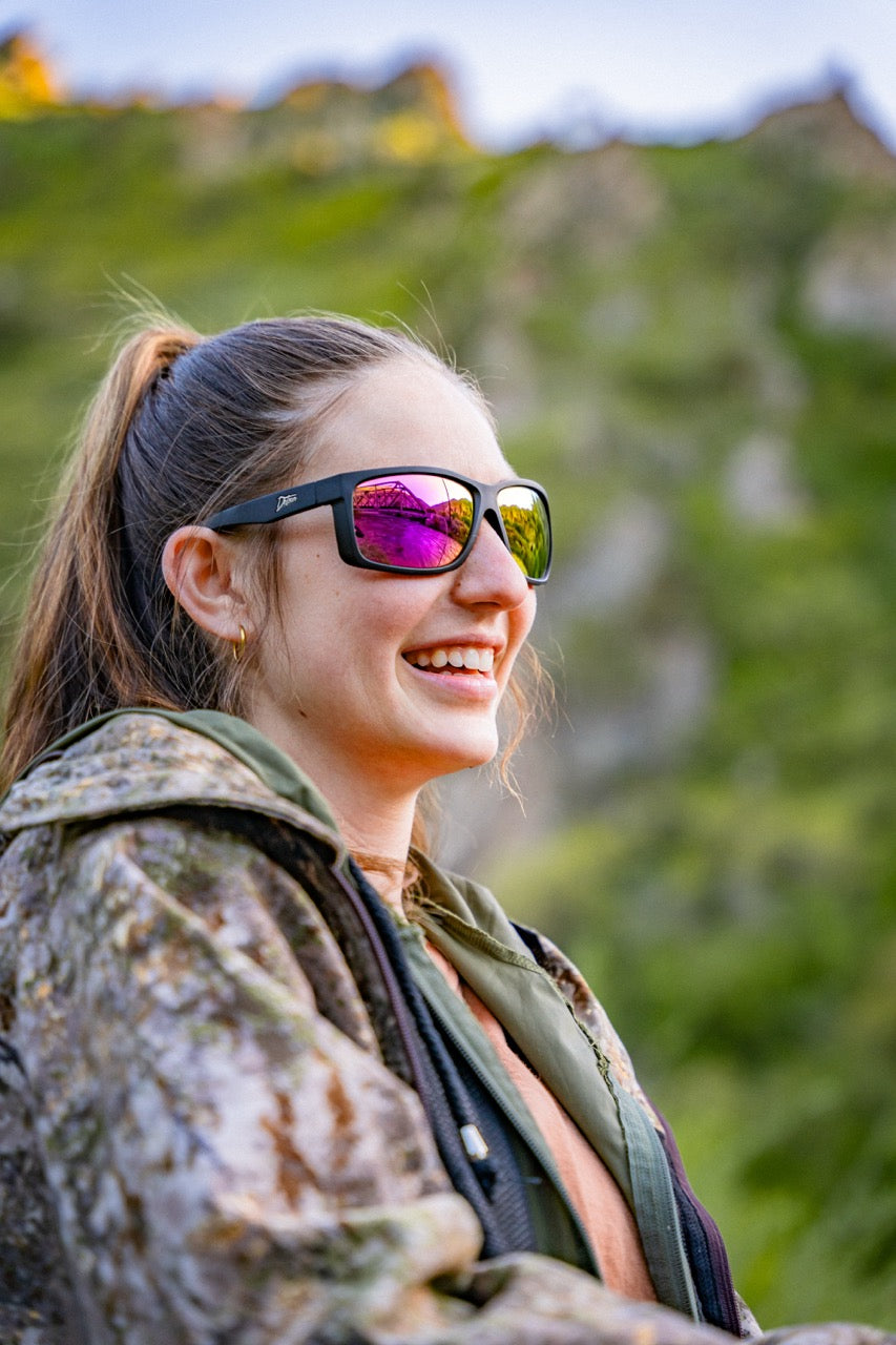 Man wearing mirrored goggles and gray beanie, holding skis in a snowy setting.